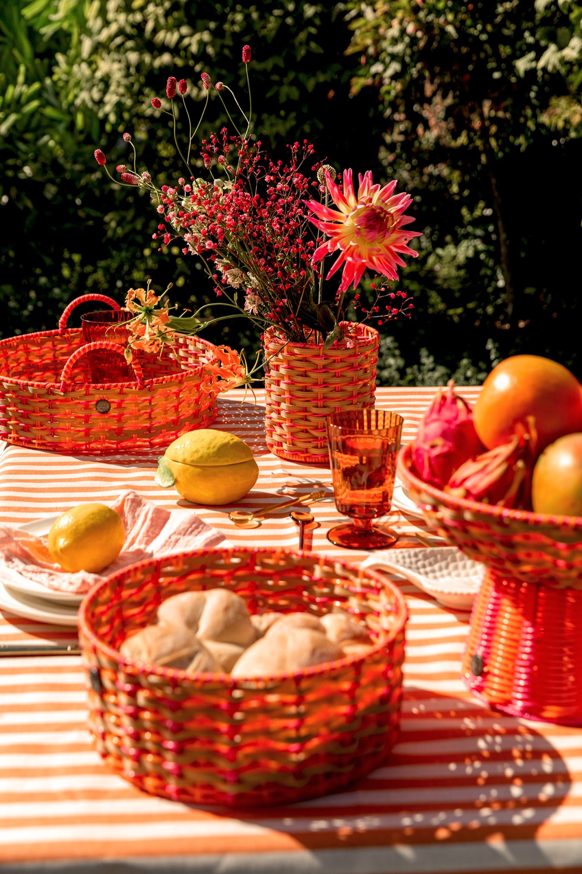 Handed By Körbe und Blumen auf einem sommerlich gedeckten Tisch im Freien