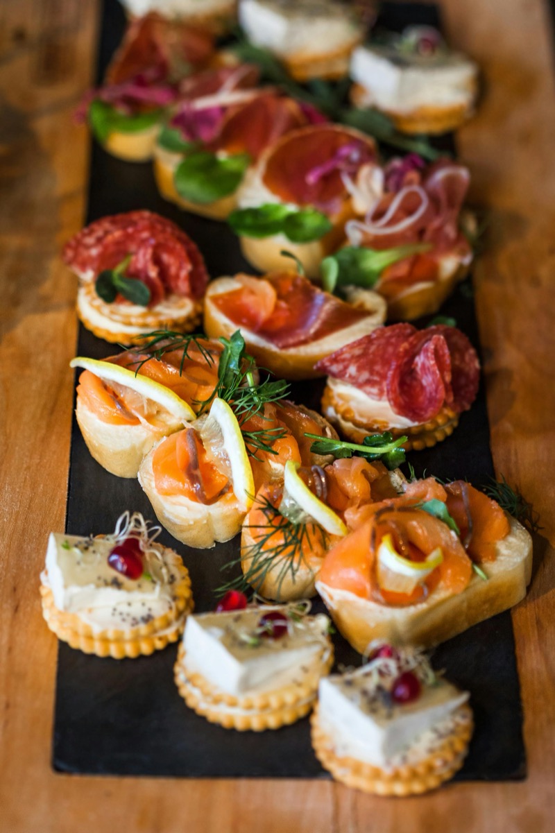 Feine Canapés mit Lachs, Salami und Brie auf Schieferplatte im Glüxstern